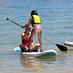 Coach explains oar to athlete on paddle board.