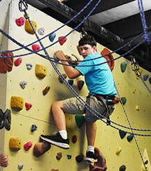 An athlete climbs an indoor rock wall.