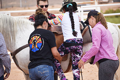 Coaches assist athlete onto horse.
